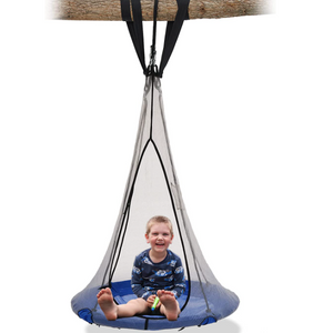 Boy sitting on a saucer round swing hanging on a tree branch